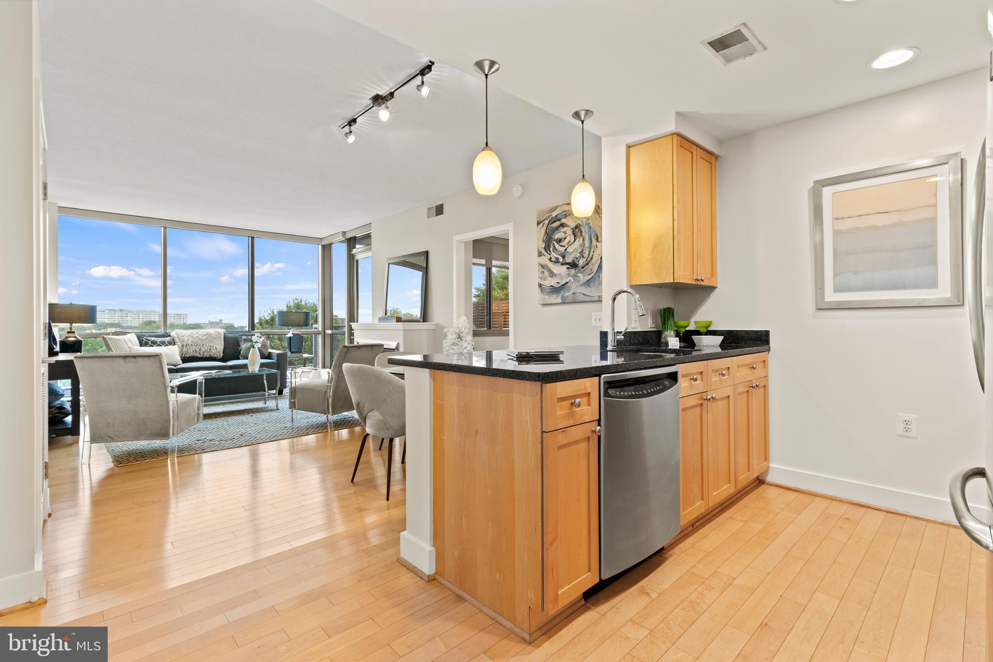 a large kitchen with kitchen island a large counter top a sink stainless steel appliances and cabinets
