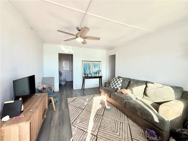 a living room with furniture a ceiling fan a lamp and a window