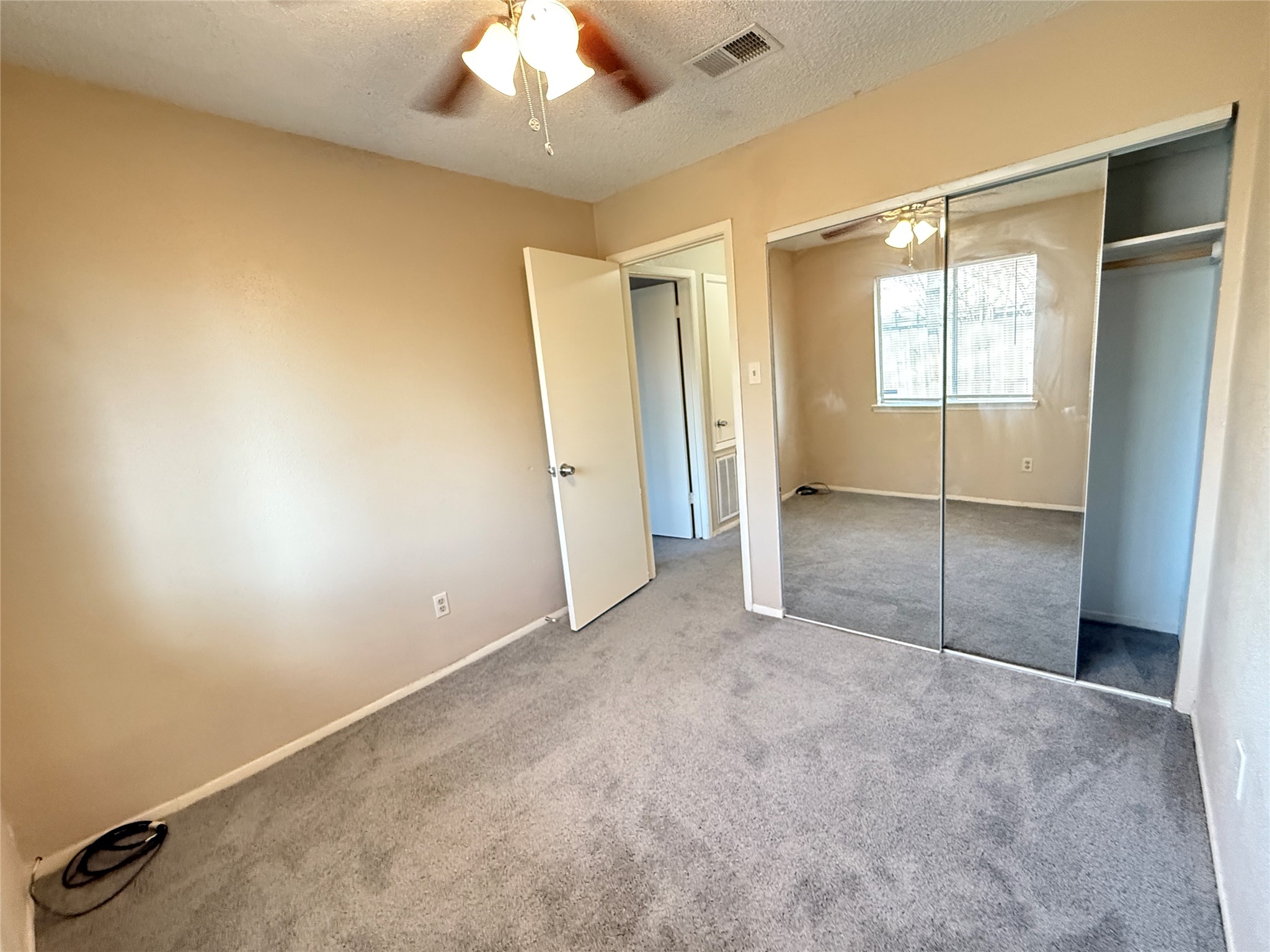 3219 Forestbrook Drive Spring, TX 77373 - Photo 11 of 16 Bedroom 2 featuring carpeted flooring, a ceiling fan, and mirrored closet doors. The room is well-lit with natural light from a window, offering a simple and clean space.