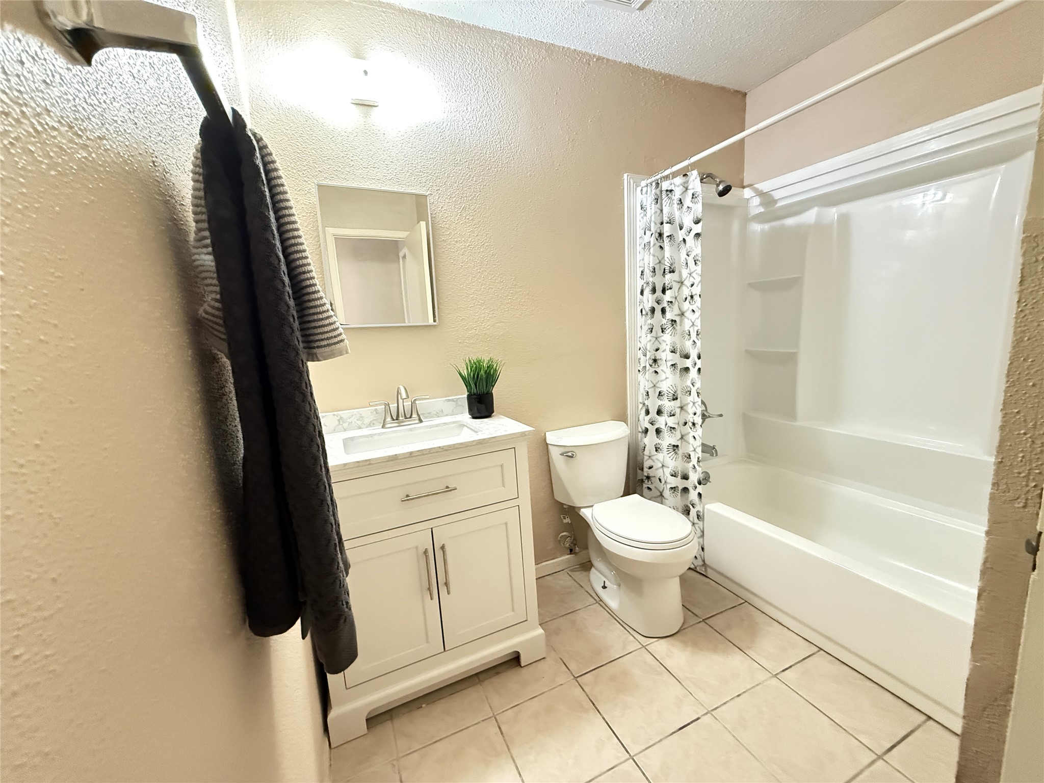 3219 Forestbrook Drive Spring, TX 77373 - Photo 13 of 16 Guest bathroom features a clean, modern design with a new marble top white vanity, a mirror, and a combined bathtub and shower. It has tiled flooring and neutral wall colors, creating a bright and welcoming space.