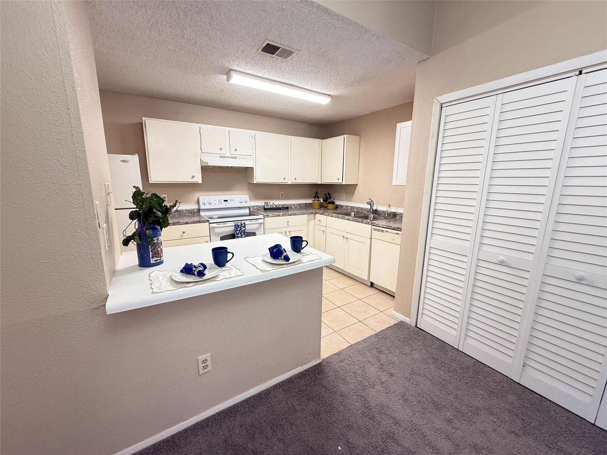 3219 Forestbrook Drive Spring, TX 77373 - Photo 3 of 16 Open concept kitchen with white cabinets and appliances, a breakfast bar, and tiled flooring. Opens into your dining area.