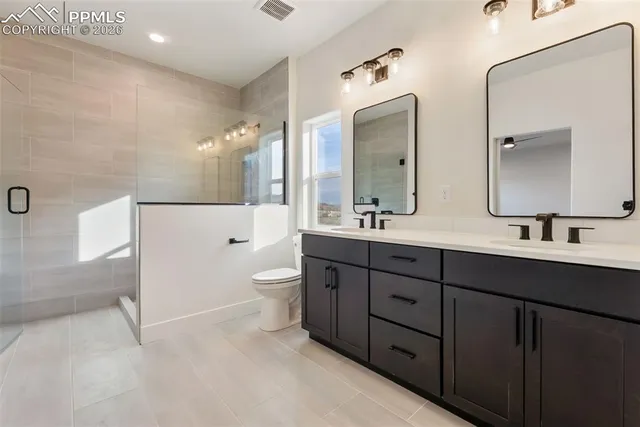 a spacious bathroom with a double vanity sink toilet mirror and bathtub