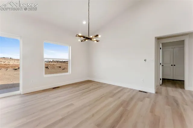an empty room with wooden floor mirror and windows