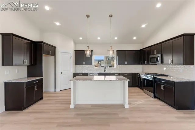 a kitchen with kitchen island stainless steel appliances a sink cabinets and wooden floor
