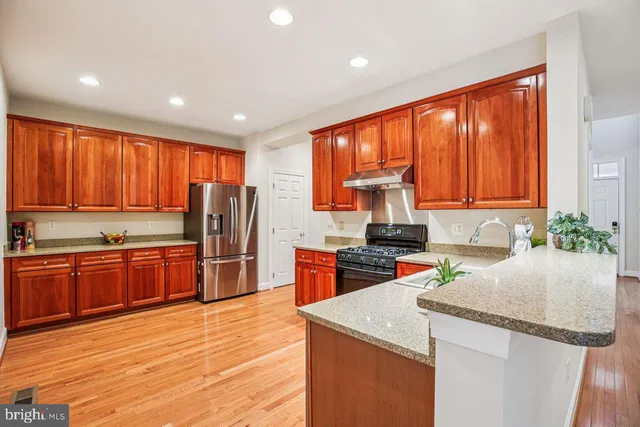 a kitchen with granite countertop a table chairs stove and wooden floor
