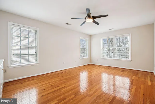 an empty room with wooden floor and a ceiling fan