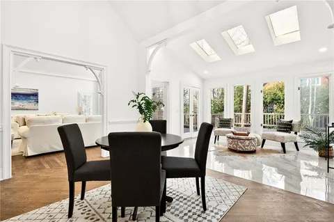 a dining room with furniture large windows and wooden floor