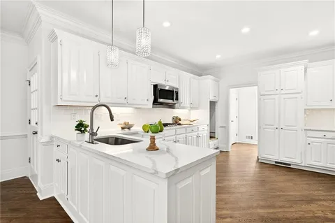 a kitchen with stainless steel appliances a white sink cabinets and wooden floor