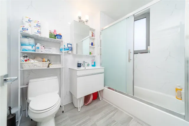 a white bath tub sitting next to a white toilet and vanity