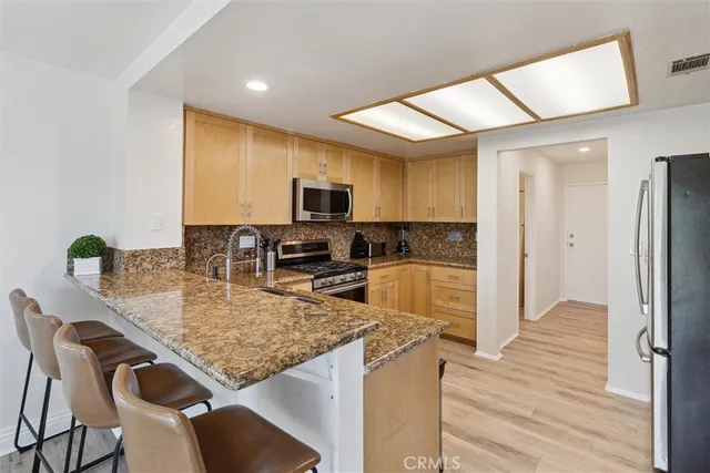 a kitchen with granite countertop kitchen island wooden cabinets and refrigerator