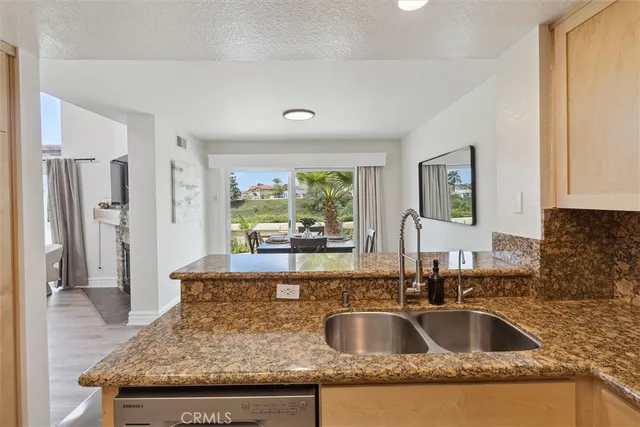 a kitchen with granite countertop a sink and a refrigerator