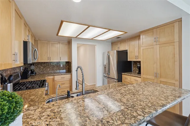a kitchen with stainless steel appliances kitchen island granite countertop a refrigerator and cabinets