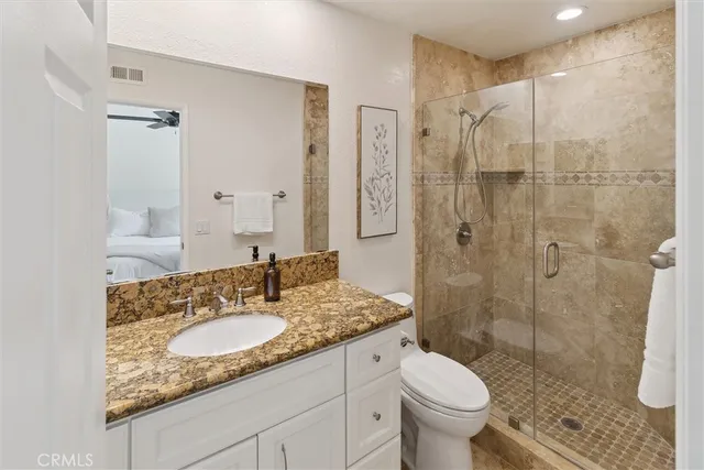 a bathroom with a granite countertop sink toilet and shower
