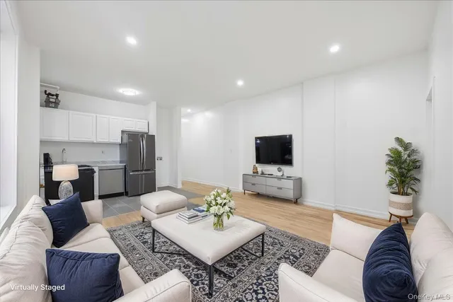 a living room with furniture kitchen view and a flat screen tv