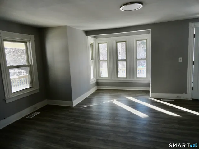 a view of an empty room with wooden floor and a window