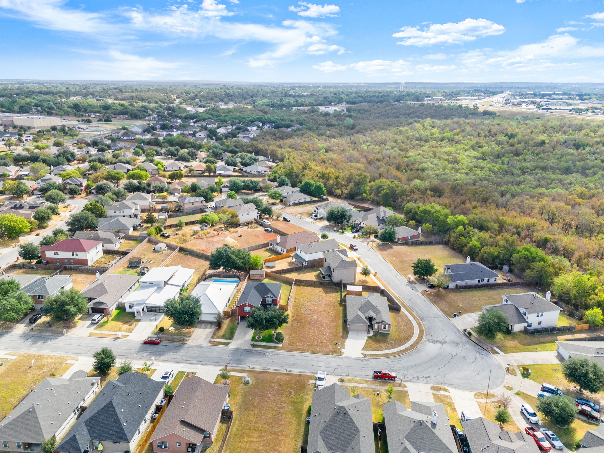 406 Gettysburg Loop Elgin, TX 78621 - Photo 8 of 8 An aerial perspective reveals a residential community nestled beside a verdant, undeveloped expanse.