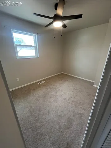 a view of an empty room with a ceiling fan and window