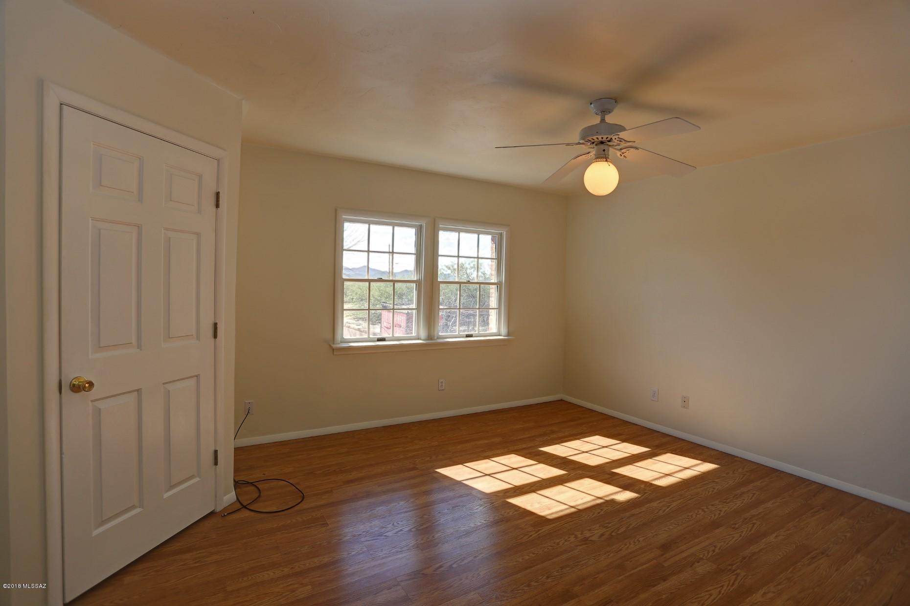 5851 South Avra Road Tucson, AZ 85735 - Photo 15 of 46 a view of empty room with wooden floor and fan
