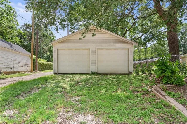 a backyard of a house with plants and large tree