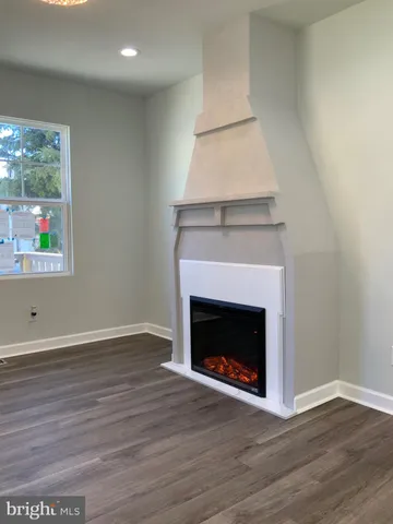 a view of an empty room with wooden floor and a fireplace