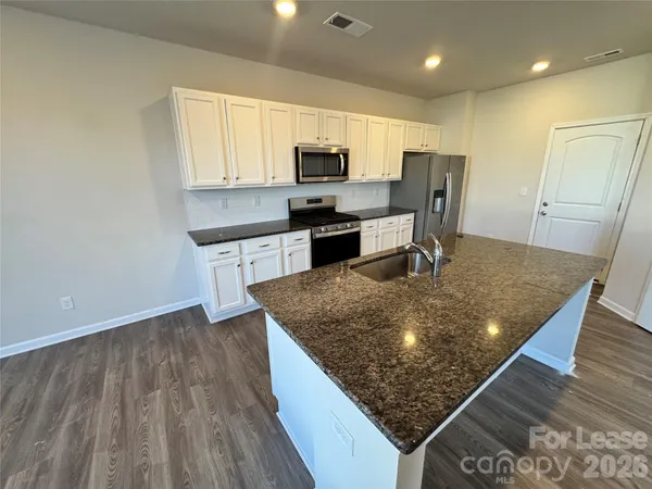 a kitchen with stainless steel appliances granite countertop a stove a sink and a microwave