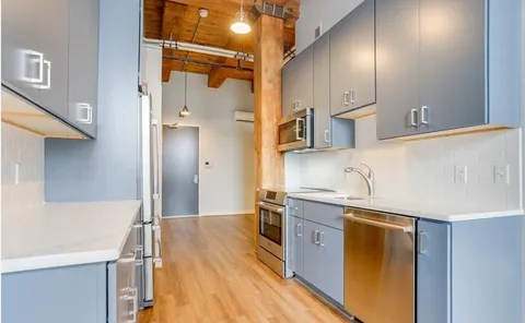 a kitchen with stainless steel appliances a refrigerator a sink and white cabinets