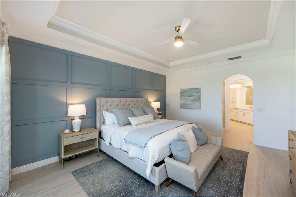16351 Viansa Way, Unit 202 Naples, FL 34110 - Photo 10 of 35 Bedroom with a decorative wall, a raised ceiling, light wood-style floors, arched walkways, and ceiling fan
