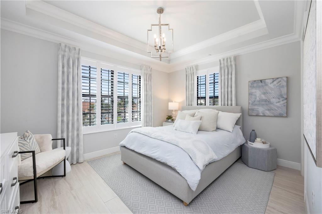 16351 Viansa Way, Unit 202 Naples, FL 34110 - Photo 15 of 35 Bedroom with suspended lighting, a raised ceiling, and light wood-style flooring