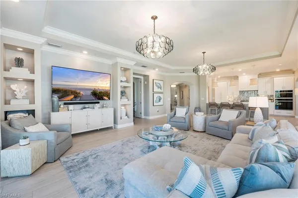 a living room with furniture kitchen view and a chandelier