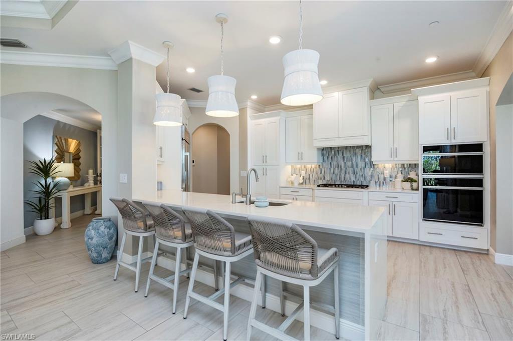 16351 Viansa Way, Unit 202 Naples, FL 34110 - Photo 4 of 35 Kitchen with a breakfast bar, arched walkways, white cabinets, tasteful backsplash, and a peninsula