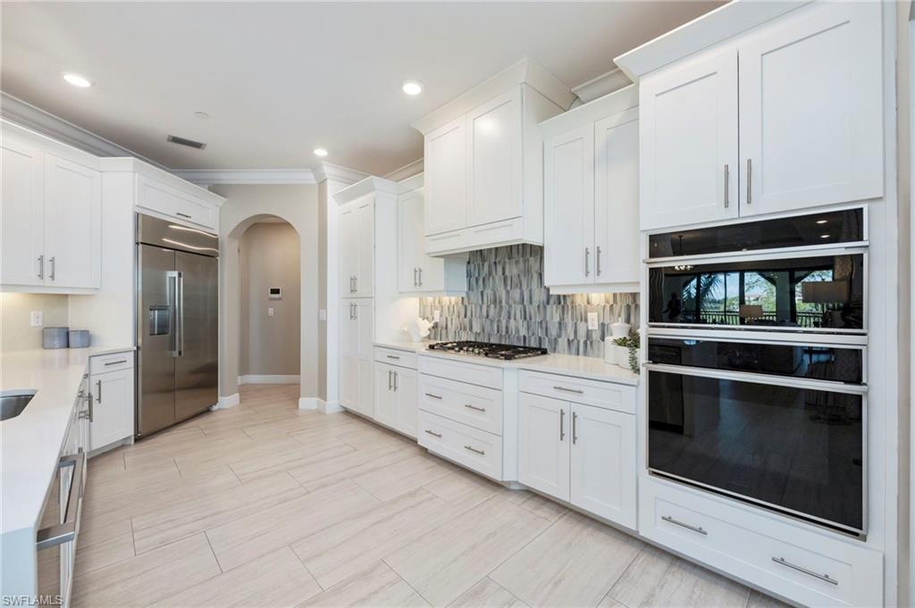 16351 Viansa Way, Unit 202 Naples, FL 34110 - Photo 5 of 35 Kitchen featuring stainless steel appliances, arched walkways, white cabinets, light stone countertops, and ornamental molding