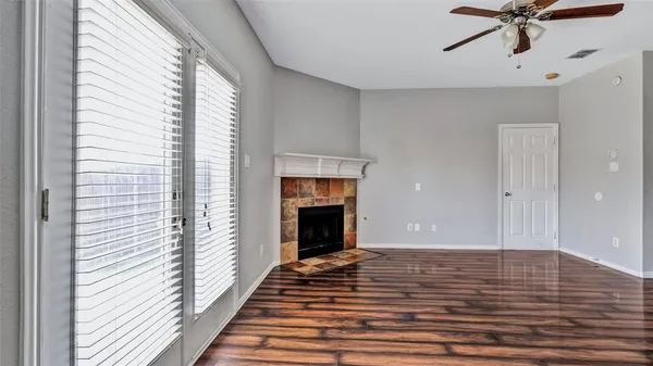 a view of an empty room with wooden floor fireplace and a window