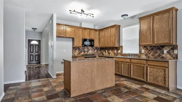 a kitchen with stainless steel appliances granite countertop a refrigerator a sink a stove a microwave and island