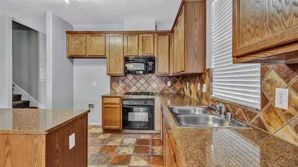 a kitchen with granite countertop a stove a sink and a microwave