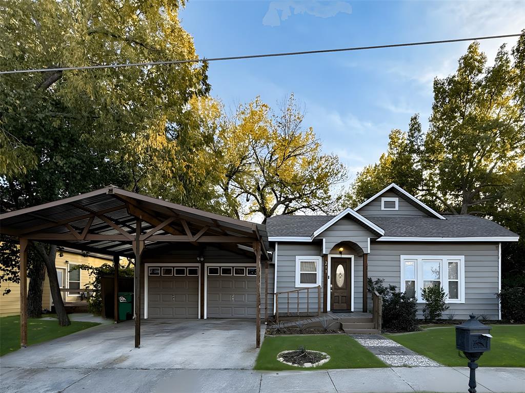 a view of a house with a small yard and a large tree