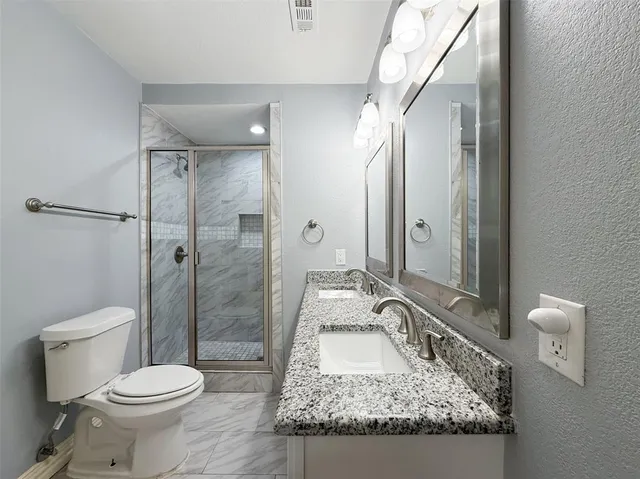 a bathroom with a granite countertop sink toilet and shower