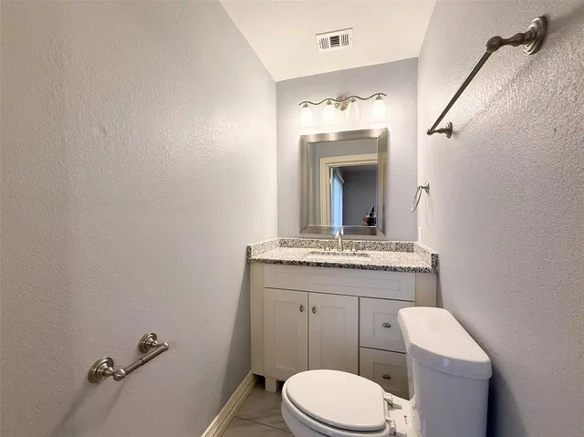 a bathroom with a granite countertop toilet sink and mirror