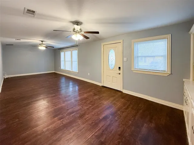 a view of an empty room with wooden floor and a window
