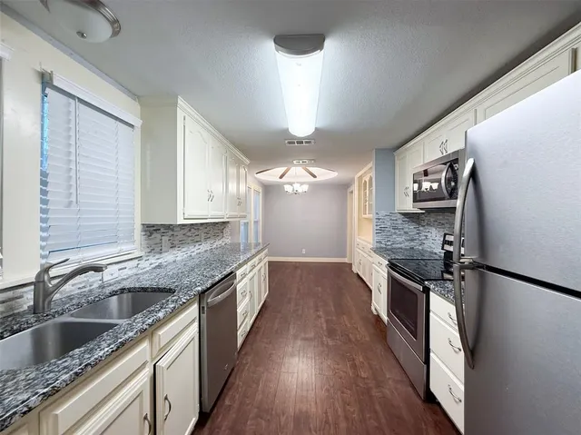 a kitchen with granite countertop stainless steel appliances a sink stove and refrigerator