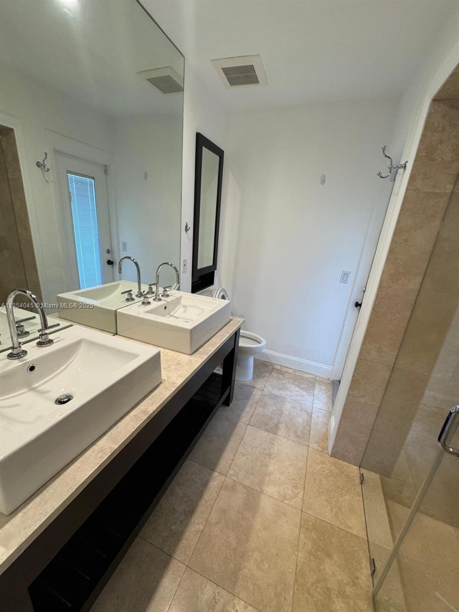 5801 Southwest 100th Street, Unit 1 Pinecrest, FL 33156 - Photo 9 of 11 a bathroom with a double vanity sink and a mirror