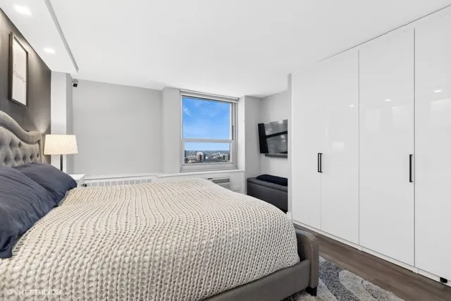 a bedroom with a large bed a flat tv screen and a night stand