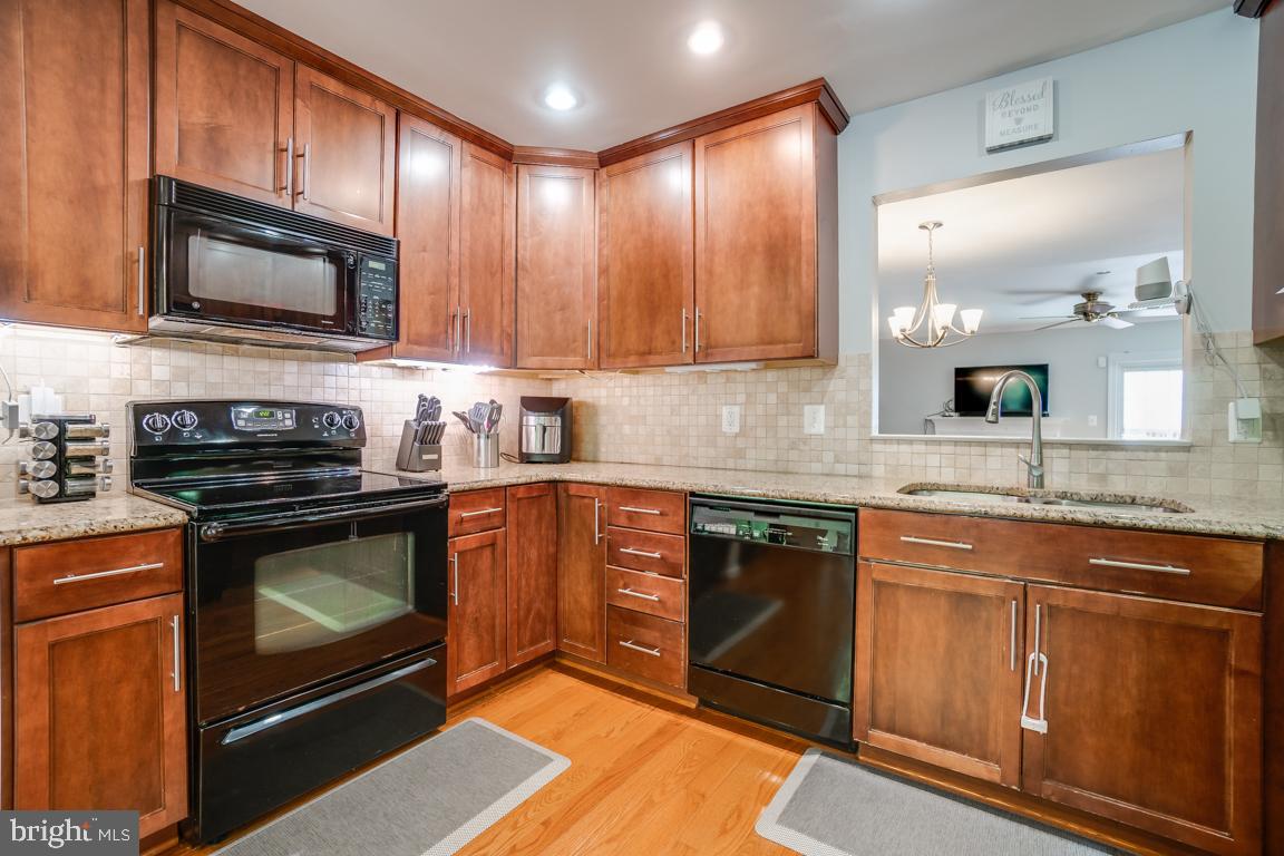 6067 Knights Ridge Way Alexandria, VA 22310 - Photo 11 of 39 a kitchen with stainless steel appliances granite countertop wooden cabinets a stove a sink and a microwave