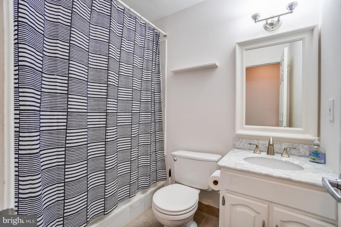 6067 Knights Ridge Way Alexandria, VA 22310 - Photo 34 of 39 a bathroom with a granite countertop toilet a sink a mirror and shower