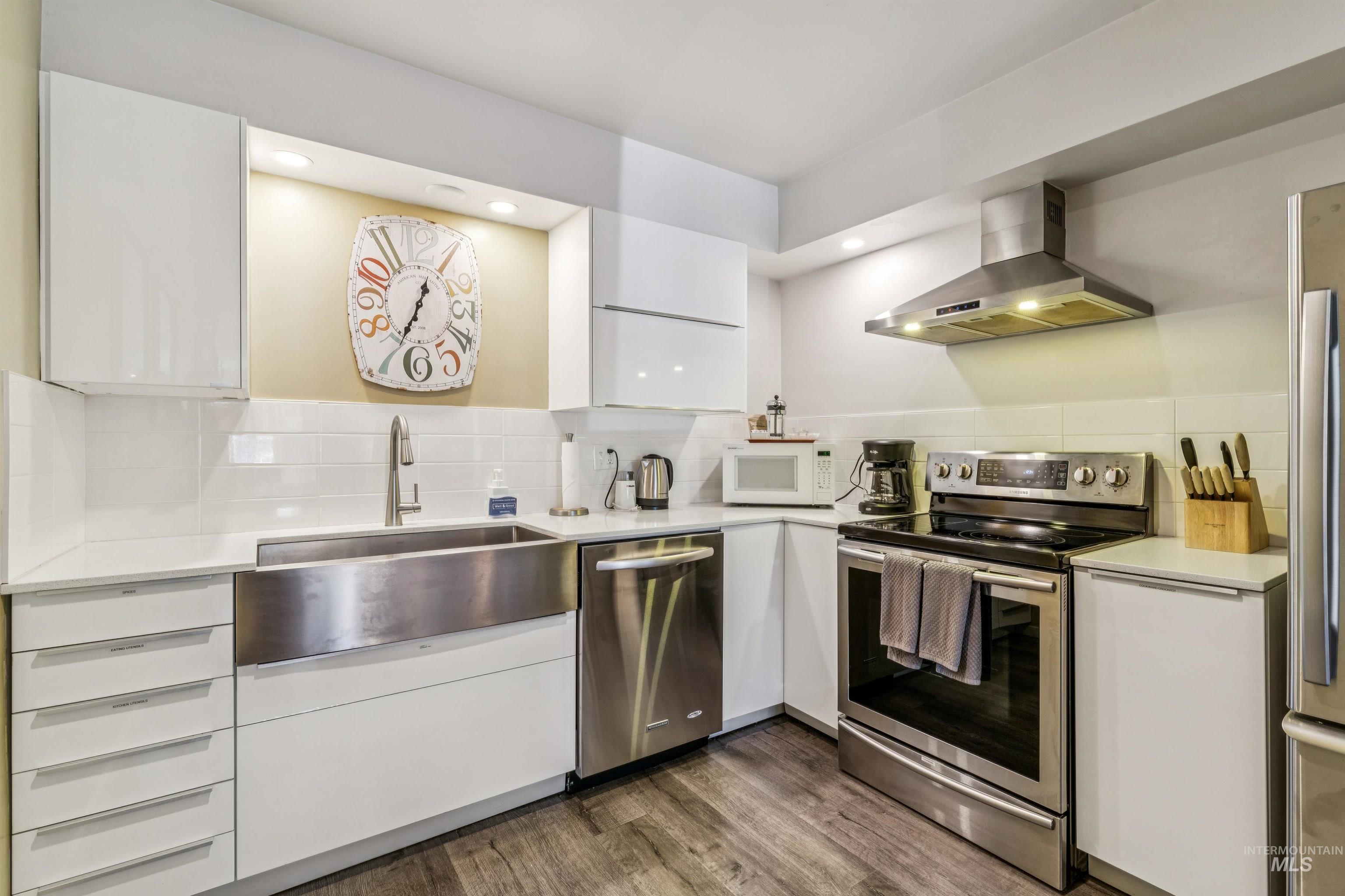 925 North 9th Street, Unit 20 Boise, ID 83702 - Photo 13 of 35 Kitchen with stainless steel appliances, extractor fan, white cabinetry, decorative backsplash, and dark wood-type flooring