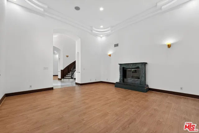 a view of an empty room with wooden floor and a fireplace