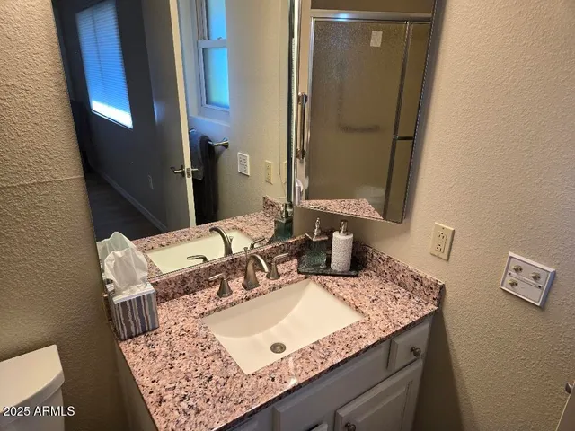 a bathroom with a granite countertop sink and a mirror