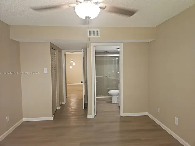a view of a bathroom with a toilet a mirror and a hardwood