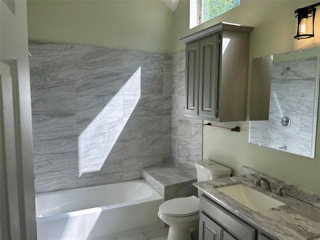 a bathroom with a granite countertop sink toilet and shower