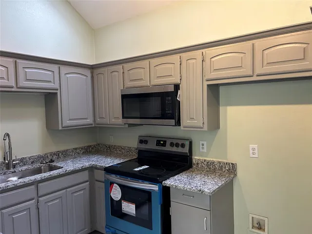 a kitchen with stainless steel appliances granite countertop a sink stove and microwave