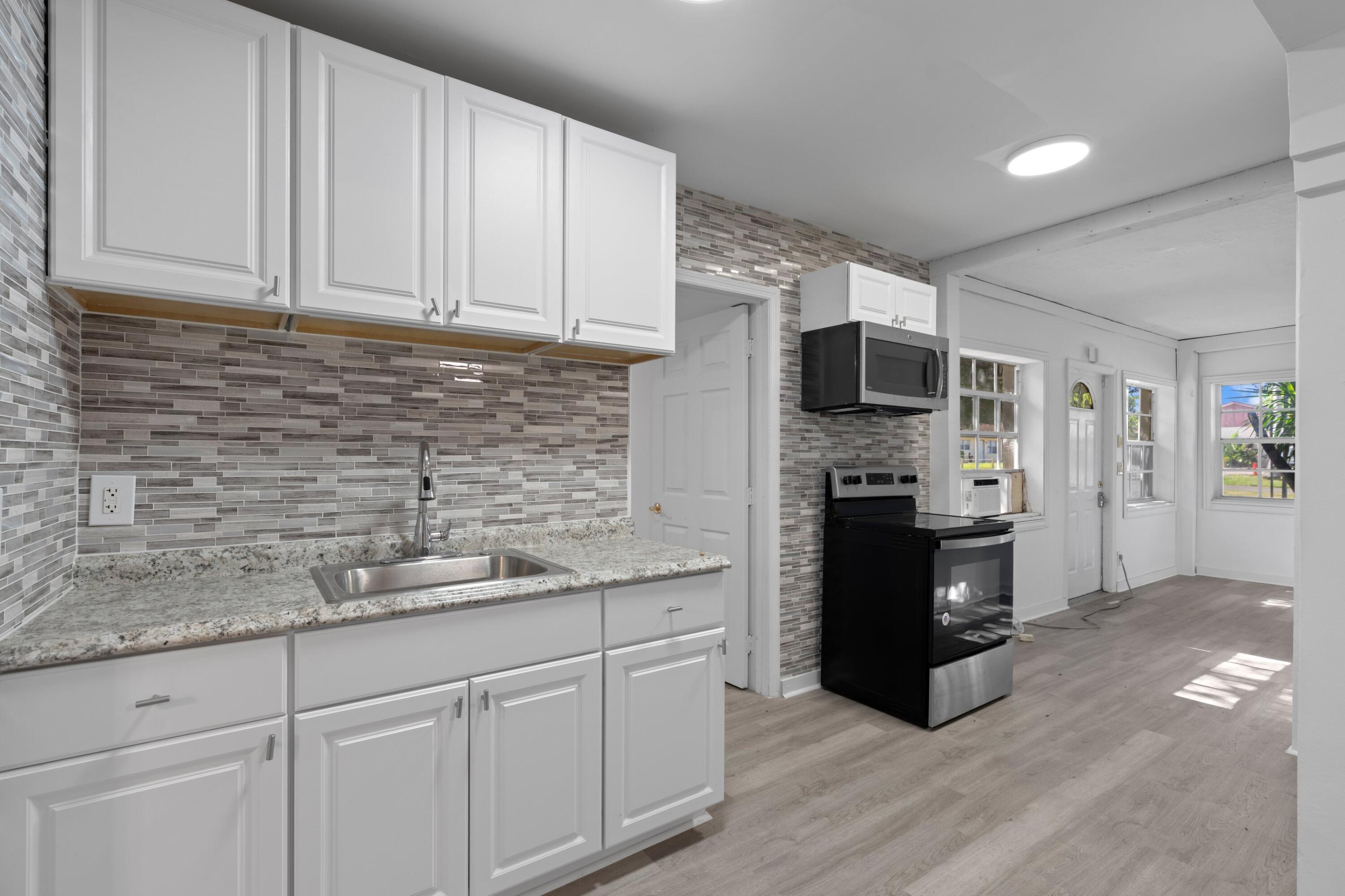 1831 Juno Road North Palm Beach, FL 33408 - Photo 12 of 37 a kitchen with stainless steel appliances granite countertop a refrigerator a stove a sink and white cabinets